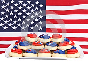 Plate of bright patriotic cookies in front of American flag