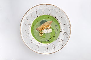 Plate of broccoli and green peas cream soup with bread toast isolated on white background