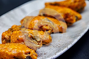 Plate of Buffalo chicken wings on a black background