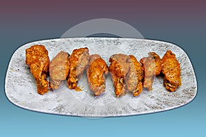 Plate of Buffalo chicken wings on a magenta and light blue background