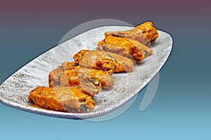 Plate of Buffalo chicken wings on a magenta and light blue background