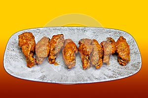 Plate of Buffalo chicken wings on a red and yellow background