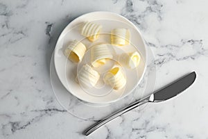 Plate with butter curls and knife on table