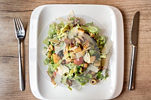 Plate of caesar salad on wooden table photo