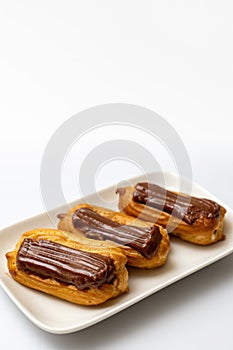 Plate cakes chocolate icing on white background