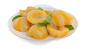 Plate with canned peach halves and mint leaves isolated on white