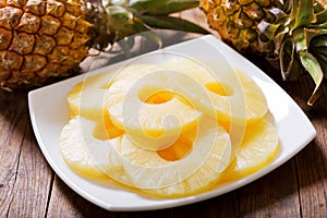 Plate of canned slices of pineapple and fresh pineapple