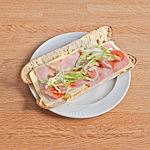 Plate with a Cheese and ham sandwich on wooden table