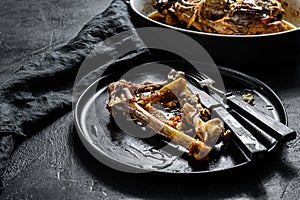 A plate of chicken bones and a chicken  skeleton in a baking dish. Leftovers from dinner. Black background. Top view