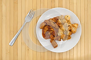 Plate with chicken chunks in barbecue sauce plus potatoes