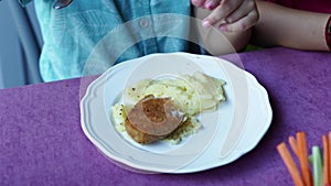 plate. the child eats mashed potatoes and cutlets.