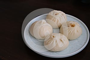 A plate of Chinese pan-fried pork buns Sheng Jian Bao on table