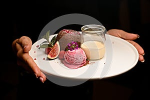 plate with chocolate cake with ice and jar of cream in female hands