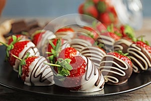 Plate with chocolate covered strawberries on table