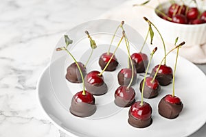 Plate of chocolate dipped cherries on marble table