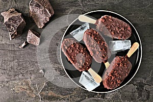 Plate of chocolate dipped ice cream bars with nuts over a dark slate background