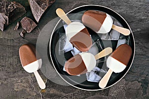 Plate of chocolate dipped vanilla ice cream bars over a dark slate background