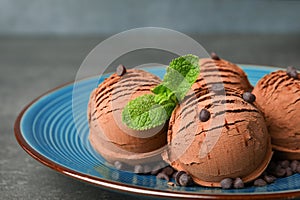 Plate of chocolate ice cream with mint on grey table