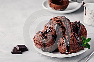 A plate of chocolate ice cream scoops with chocolate sauce