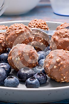 A plate of chocolate nut clusters with blueberries