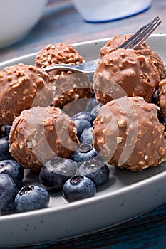 A plate of chocolate nut clusters with blueberries