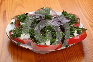 A plate with chopped tomatoes with mayonnaise, chopped dill and basil on a table