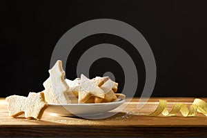 Plate with christmas cookies sprinkled with icing sugar isolated black