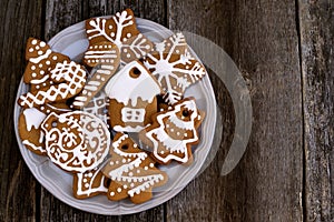 Plate with Christmas cookies on wood background, top view