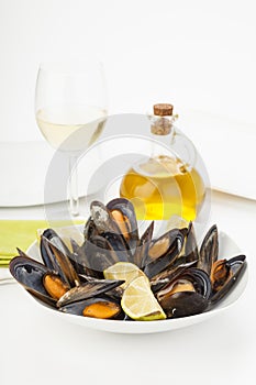 Plate of coocked mussels with lemon over white