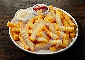 Plate of crinkle cut French fries with dips