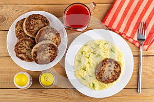 Plate with cutlets, tomato juice, plate with fried cutlet and mashed potato, salt and pepper, fork on napkin on table. Top view