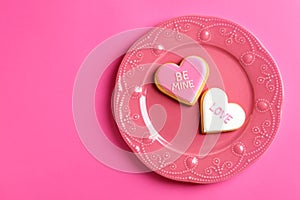 Plate with decorated heart shaped cookies and space for text on color background, top view.