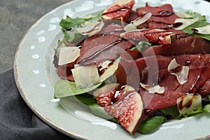 Plate with delicious bresaola salad on grey table, closeup