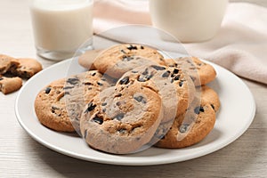 Plate with delicious chocolate chip cookies on white wooden table, closeup