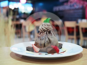 A plate of delicious chocolate crepe with vanilla ice cream inside, decorated with fresh strawberry and brownie.