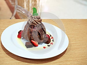A plate of delicious chocolate crepe with vanilla ice cream inside, decorated with fresh strawberry and brownie.