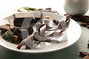 Plate with delicious chocolate, nuts and shavings on table