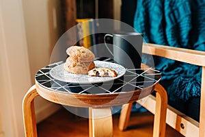 Plate of delicious cookies next to a black mug of coffee on a black table in a coffee house