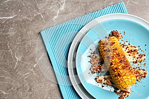 Plate with delicious grilled corn cob and spices on table