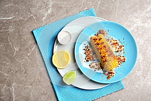 Plate with delicious grilled corn cob and spices on table