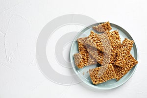 Plate with delicious kozinaki pieces on white table, top view. Space for text