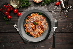 Plate with delicious pasta bolognese on dark wooden table