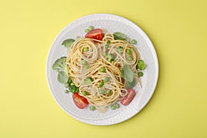 Plate of delicious pasta primavera on yellow background, top view