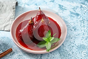 Plate with delicious poached pears in red wine on color table