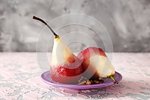 Plate with delicious poached pears in red wine on color table