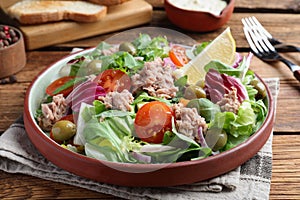 Plate of delicious salad with canned tuna and vegetables served on wooden table