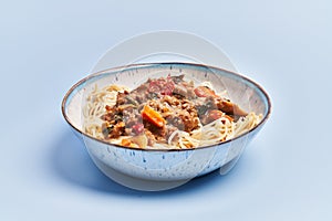 Plate of delicious spaghettis with meat and vegetables over blue background