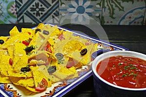 A plate of delicious tortilla nachos with melted cheese sauce, c
