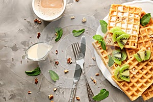 Plate with delicious waffles, sauce and cup of coffee on grey table