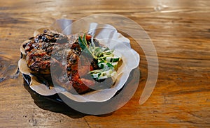 A plate of delicious whole roast chicken on a wooden table.